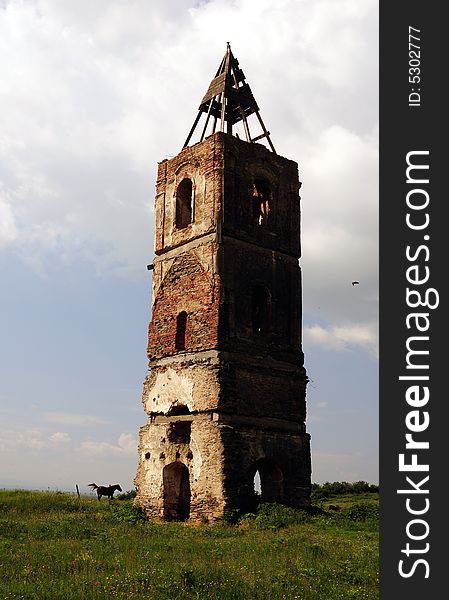 An old tower in the middle of a field with a horse