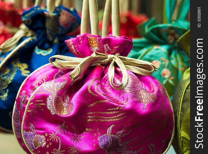 Embroidered Chinese Silk Pouches of various colors and design hung up for sale