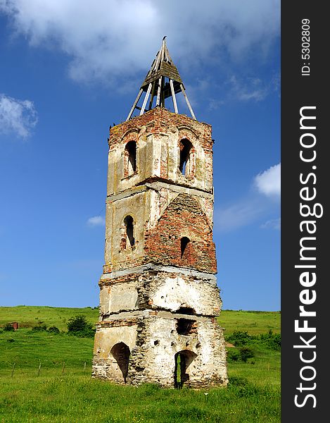 An old tower in the middle of a field with a horse