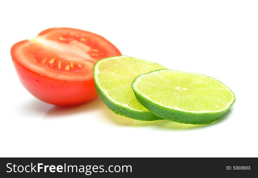 Lime and a tomato on white. Isolation, shallow DOF.