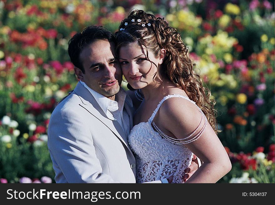 Groom and bride in the flower field holding wreath