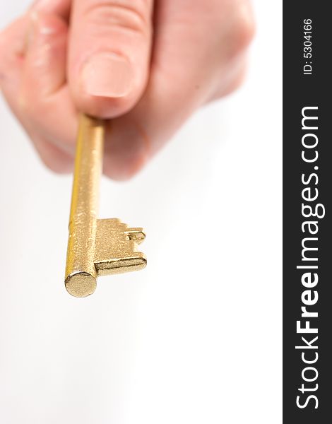 Fingers holding Golden key over white