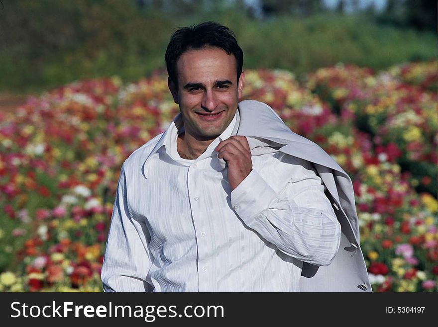 Groom in the flower field holding his coat