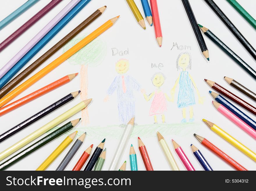 Multicolored pencils at a white paper with a child's family picture. Multicolored pencils at a white paper with a child's family picture