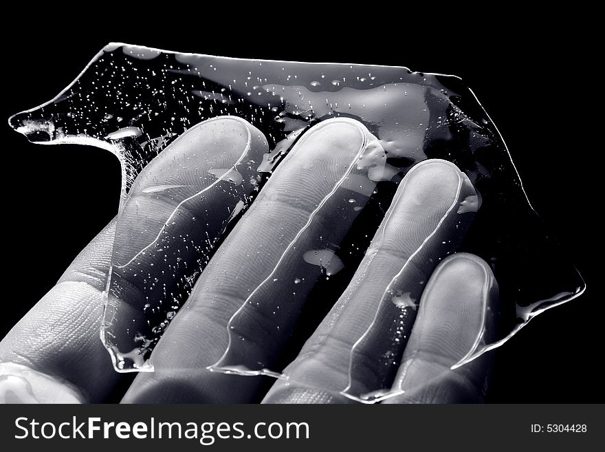 Hand, keeping splinter of ice on black background