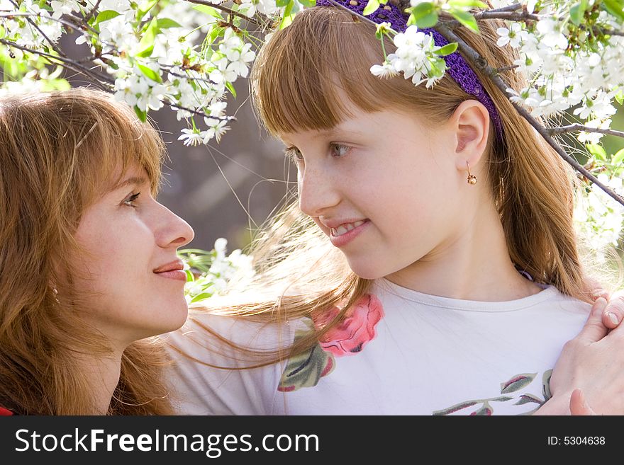 Mother and teenager daughter in middle of blossoming tree. Mother and teenager daughter in middle of blossoming tree