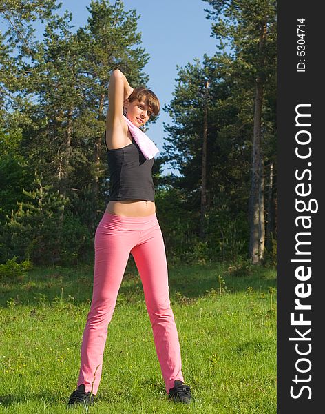 Young girl doing gymnastics in the nature with towel around neck. Young girl doing gymnastics in the nature with towel around neck