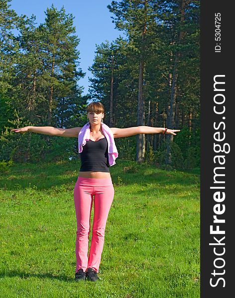 Young girl doing gymnastics in the nature with towel around neck. Young girl doing gymnastics in the nature with towel around neck