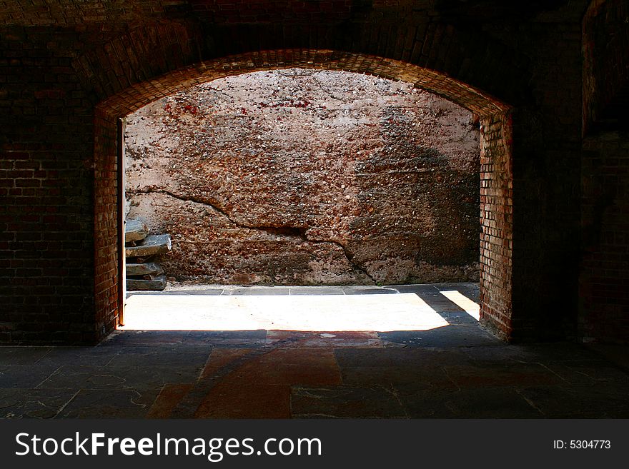 A brick arch way with daylight shinny through.