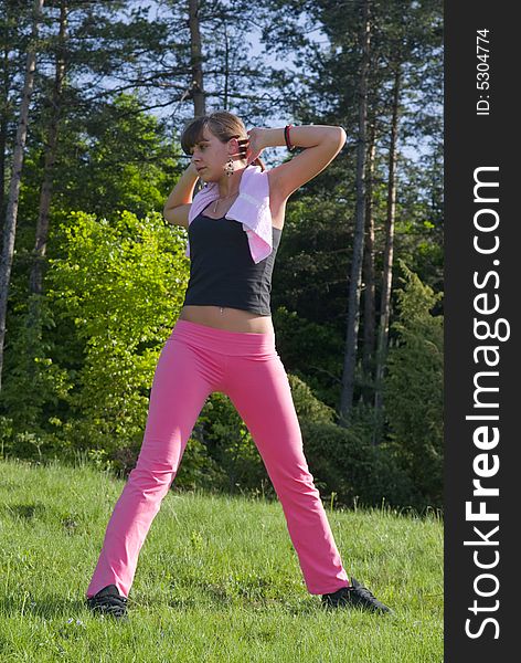 Young girl doing gymnastics in the nature with towel around neck. Young girl doing gymnastics in the nature with towel around neck