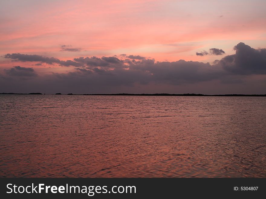 The sky and water turning pink during a sunset. The sky and water turning pink during a sunset.