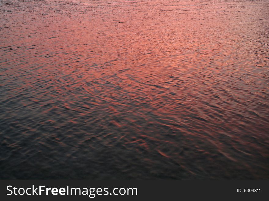 The ocean water reflecting the pink sky during sunset. The ocean water reflecting the pink sky during sunset.