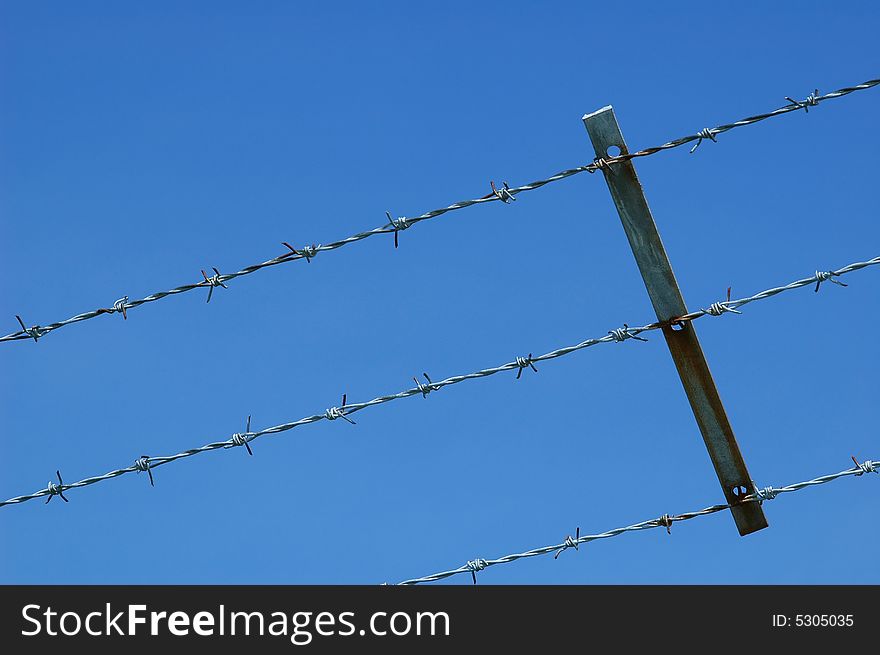 Barbed wire fencing against blue sky