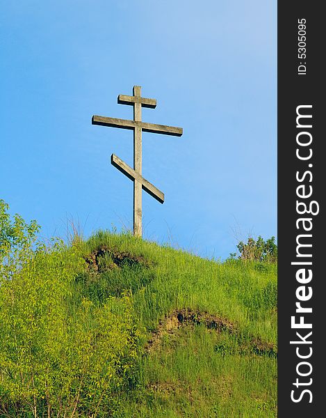 The cross against the background of the blue sky stands on the hill. The cross against the background of the blue sky stands on the hill