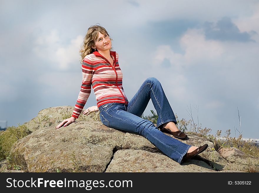 Girl sits on stones and looks in the sky. Girl sits on stones and looks in the sky