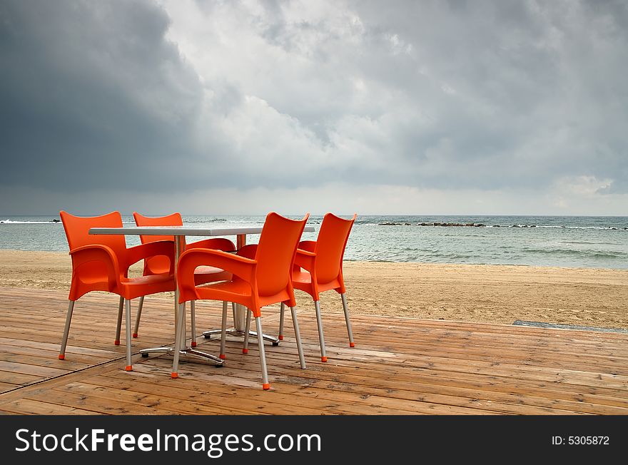 Rainy day at beach with empty cafe table on foregrund. Rainy day at beach with empty cafe table on foregrund