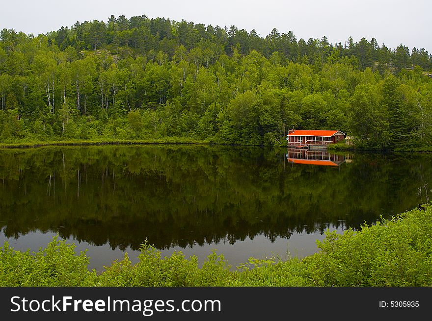 A small red house by a calm lake