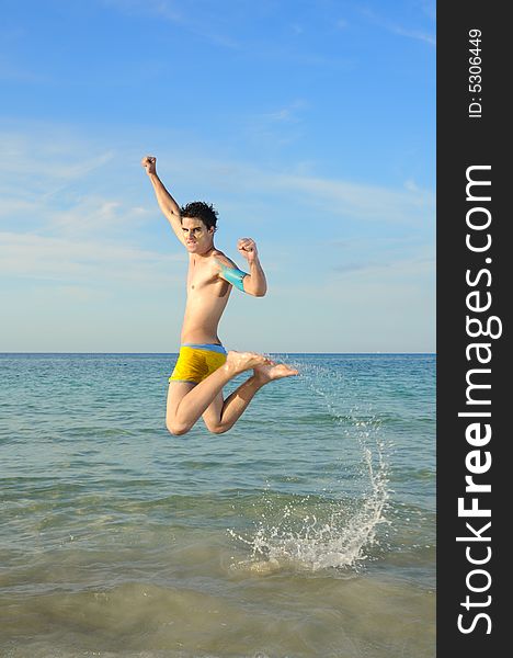Portrait of young male jumping of joy against tropical beach background. Portrait of young male jumping of joy against tropical beach background