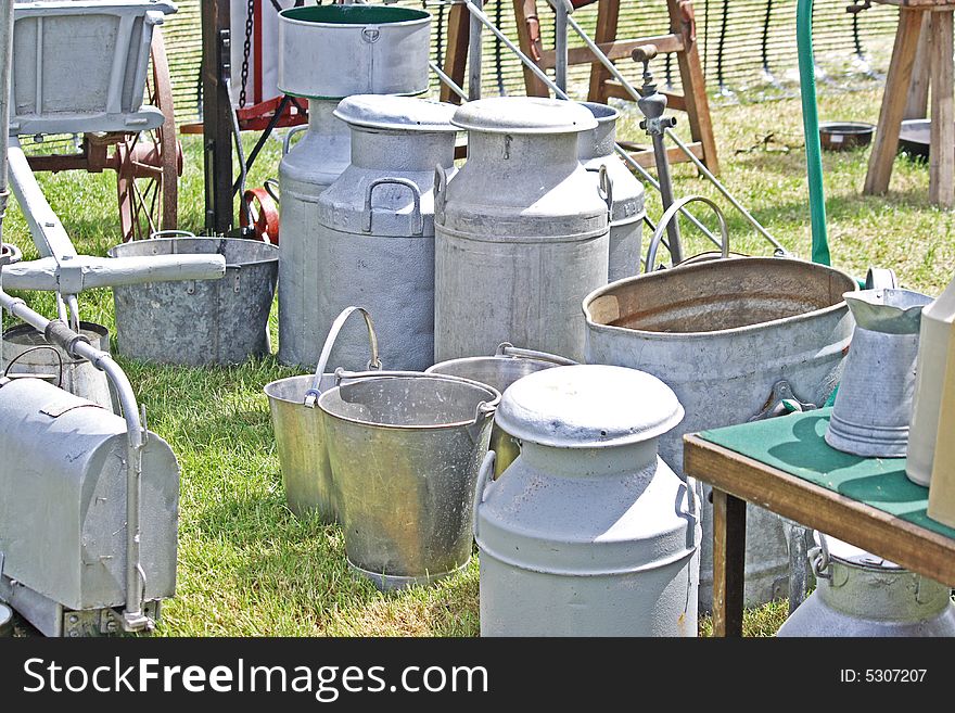 Old galvanised farm milk churns and buckets sitting on the grass. Old galvanised farm milk churns and buckets sitting on the grass