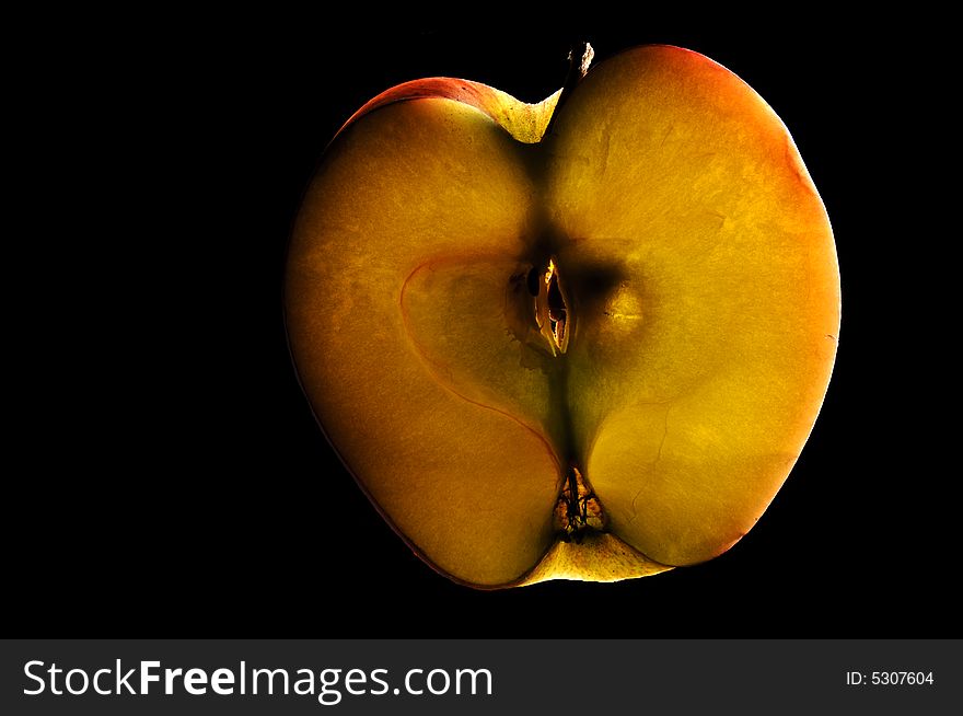Backlit apple slice on isolated black background