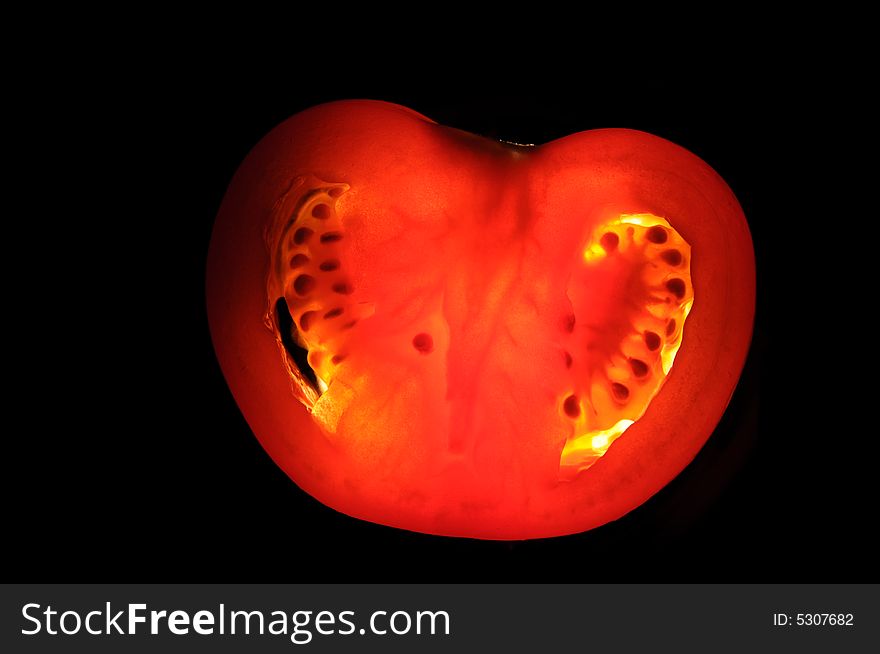 Backlit tomato slice on isolated black background