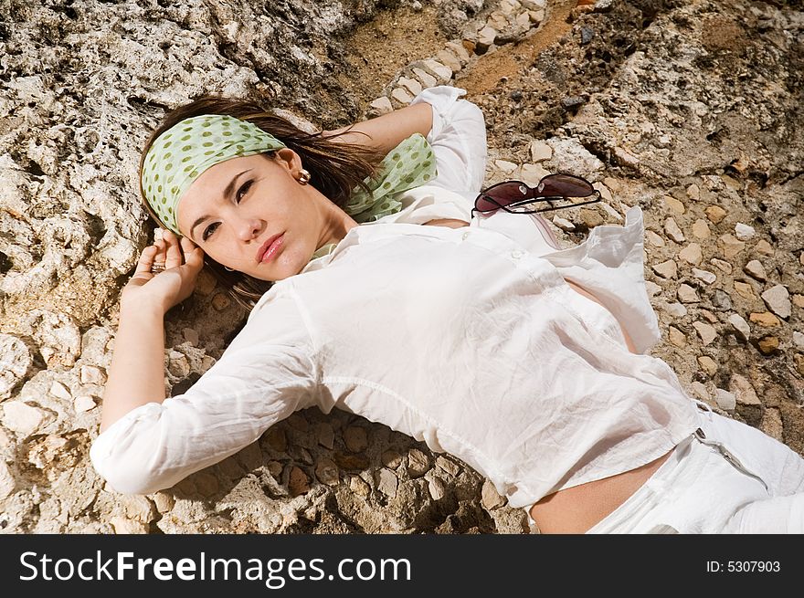 Portrait of fashion female lying on rock background. Portrait of fashion female lying on rock background