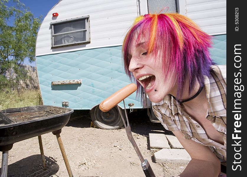 Girl in front of a trailer with a hotdog and a barbecue. Girl in front of a trailer with a hotdog and a barbecue