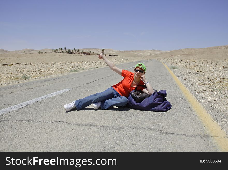 A young female hitch-hiker with her luggage. A young female hitch-hiker with her luggage