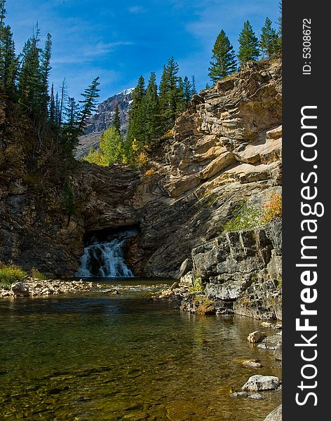 In Montana's Glacier National Park, this is a view of Hidden Falls as it comes out of the mountain with Hidden Creek in the foreground.