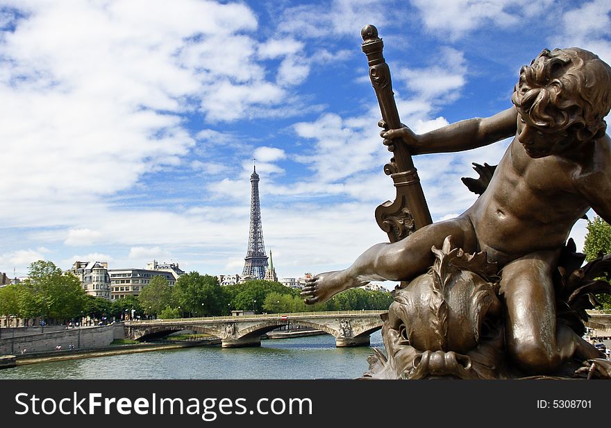 Statue of a cherub on the Alexander III bridge in Paris with the Eiffel Tower on background.