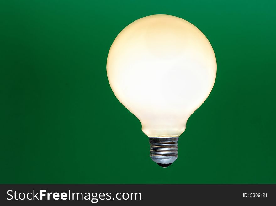 One glowing light bulb on a green background.