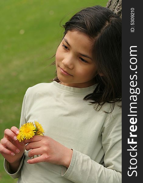 Girl holding dandelions with thoughtful expression. Girl holding dandelions with thoughtful expression