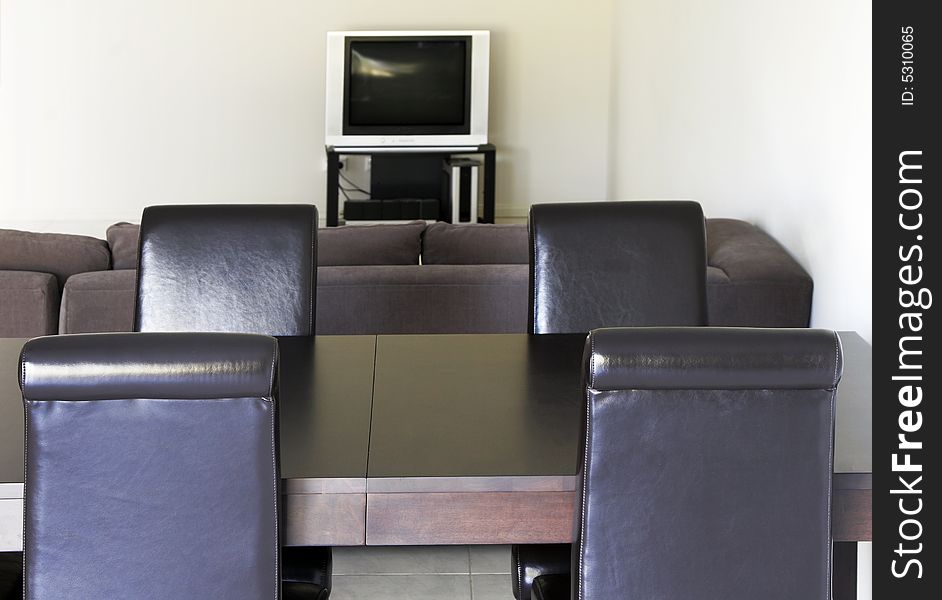 TV In Modern Living Room - White Tiles, Dark Sofa, Table, Chairs