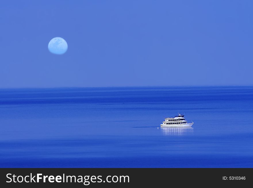 Moon over blue lake with boat