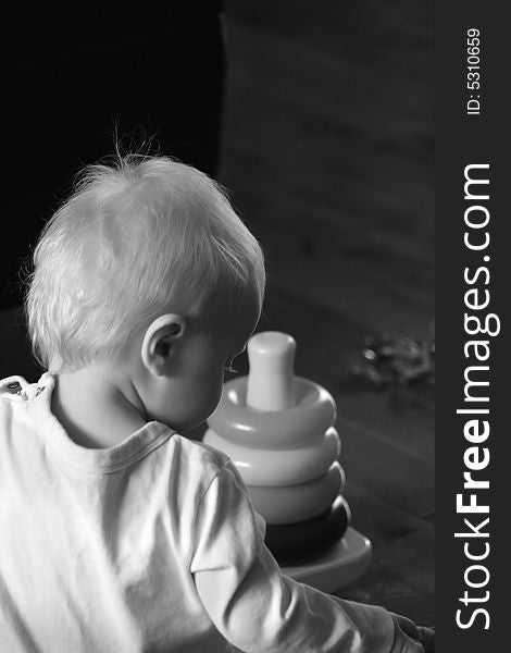 Black and white portrait of a young baby playing with some toys on the floor. Black and white portrait of a young baby playing with some toys on the floor