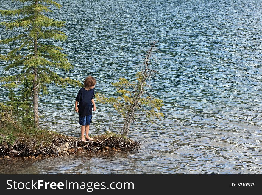 Portrait of a young boy standing on the end of a small island on a lake. Portrait of a young boy standing on the end of a small island on a lake