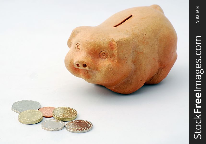 British coins and piggy bank over white. British coins and piggy bank over white