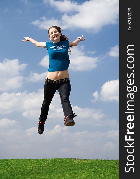 The happy jumping girl on a background of the blue sky