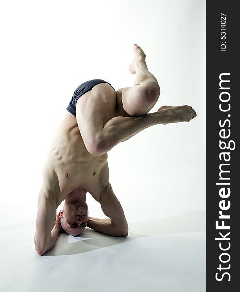 Young professional muscular male dancer in yoga position