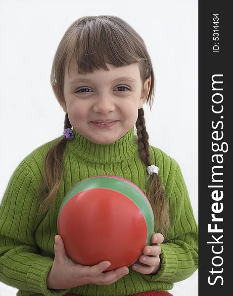 The little girl holds a red ball in hands. The little girl holds a red ball in hands