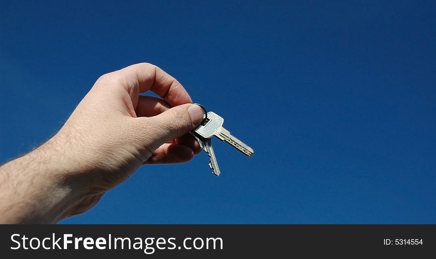 Keys in a hand on a background of the sky