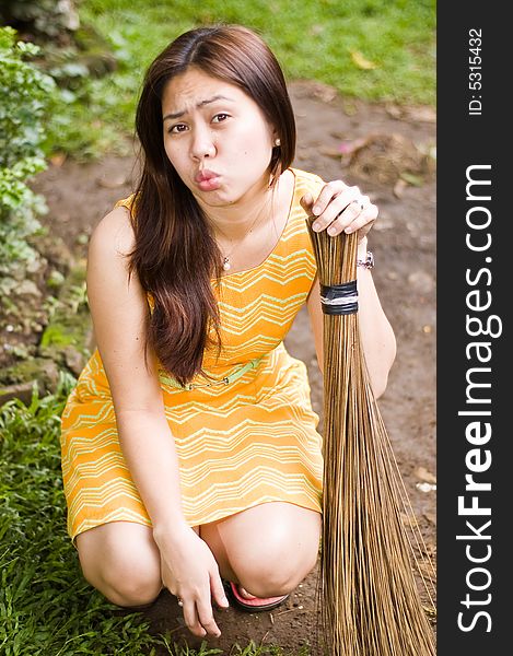 Asian girl holding a broom while lips are puckered. Asian girl holding a broom while lips are puckered