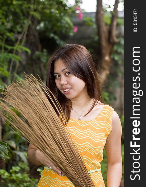 A beautiful lady holding stick broom while cleaning garden. A beautiful lady holding stick broom while cleaning garden