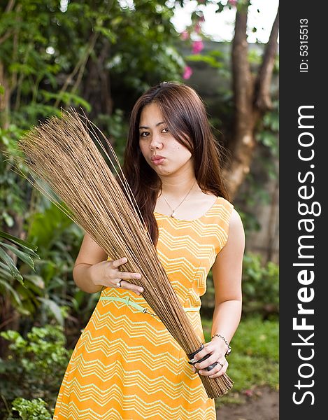 A beautiful lady holding stick broom while cleaning garden. A beautiful lady holding stick broom while cleaning garden