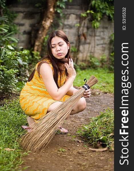 Gorgeous lady holding a broom crouched on garden. Gorgeous lady holding a broom crouched on garden
