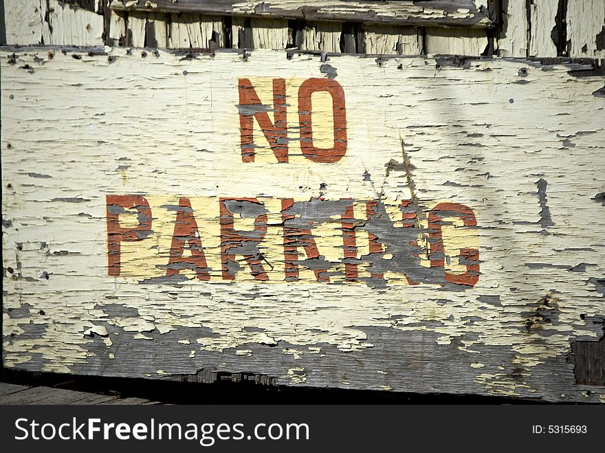 Old weathered no parking warning painted on old rotting peeling doors in portland maine