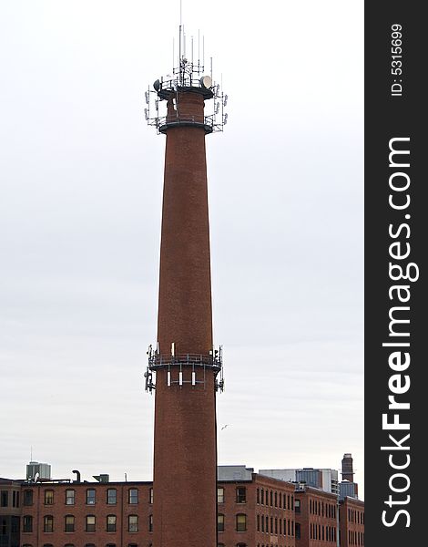 Old brick smokestack in boston massachusetts with satellite dishes and antennas. Old brick smokestack in boston massachusetts with satellite dishes and antennas