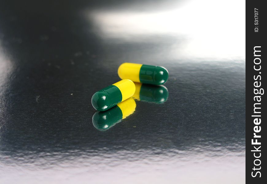 Green and yellow capsules in a silver background