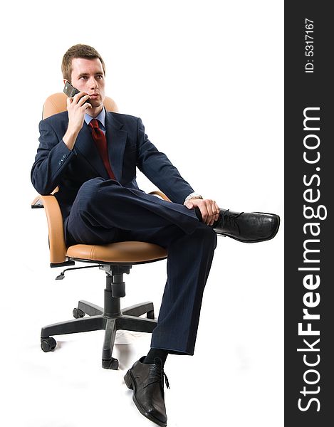 Businessman sitting on an armchair with cell phone. Isolated