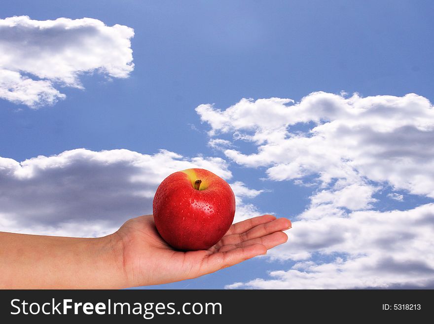 Apple in palm with sky background with beads of water on apple